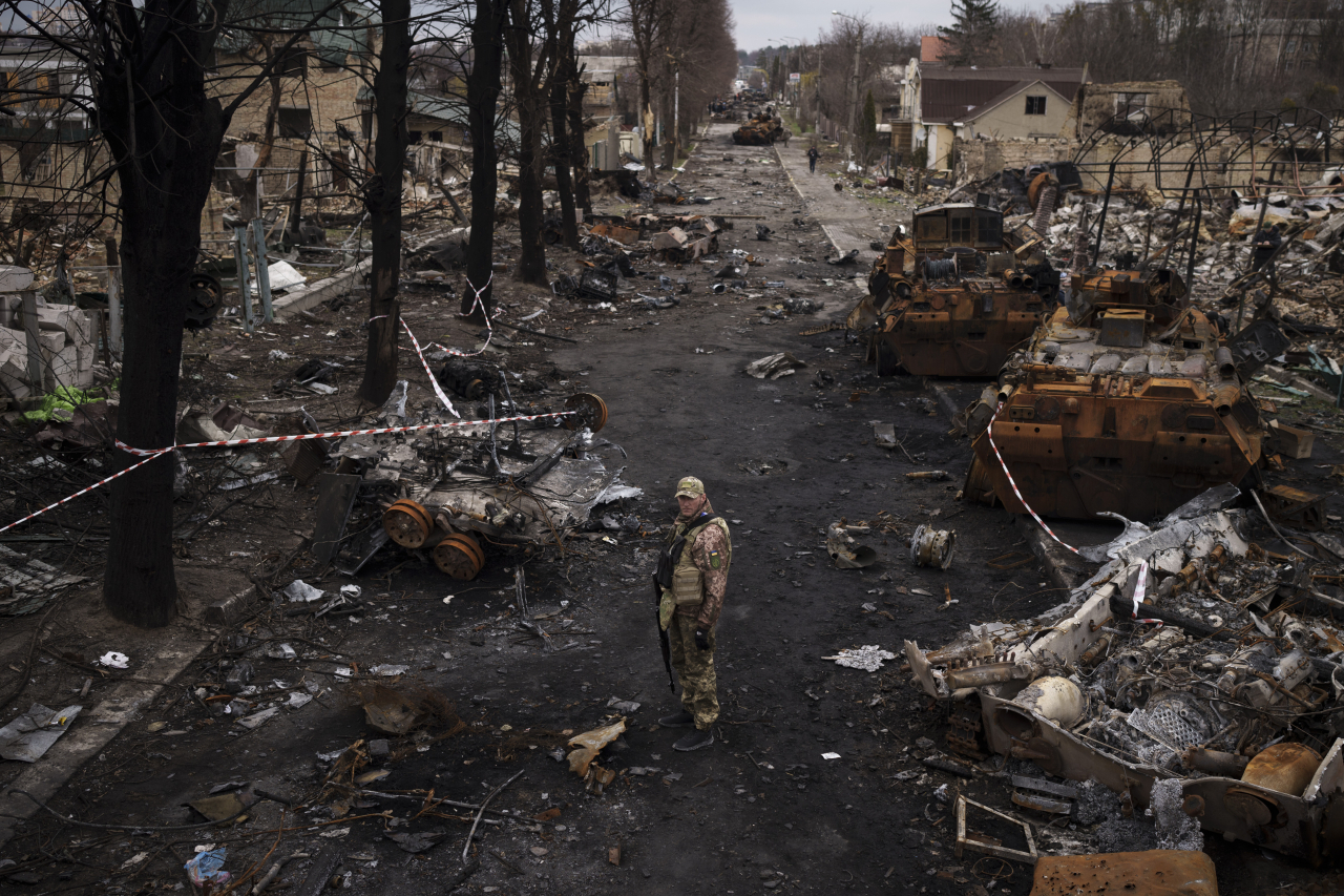 A Ukrainian serviceman stands amid destroyed Russian tanks in Bucha, on the outskirts of Kyiv, Ukraine, Wednesday. (AP-Yonhap)