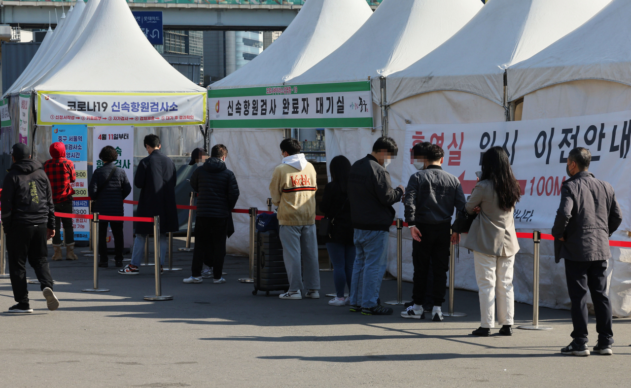 People line up to be tested of COVID-19 at a testing booth near Seoul Station, Friday. (Yonhap)