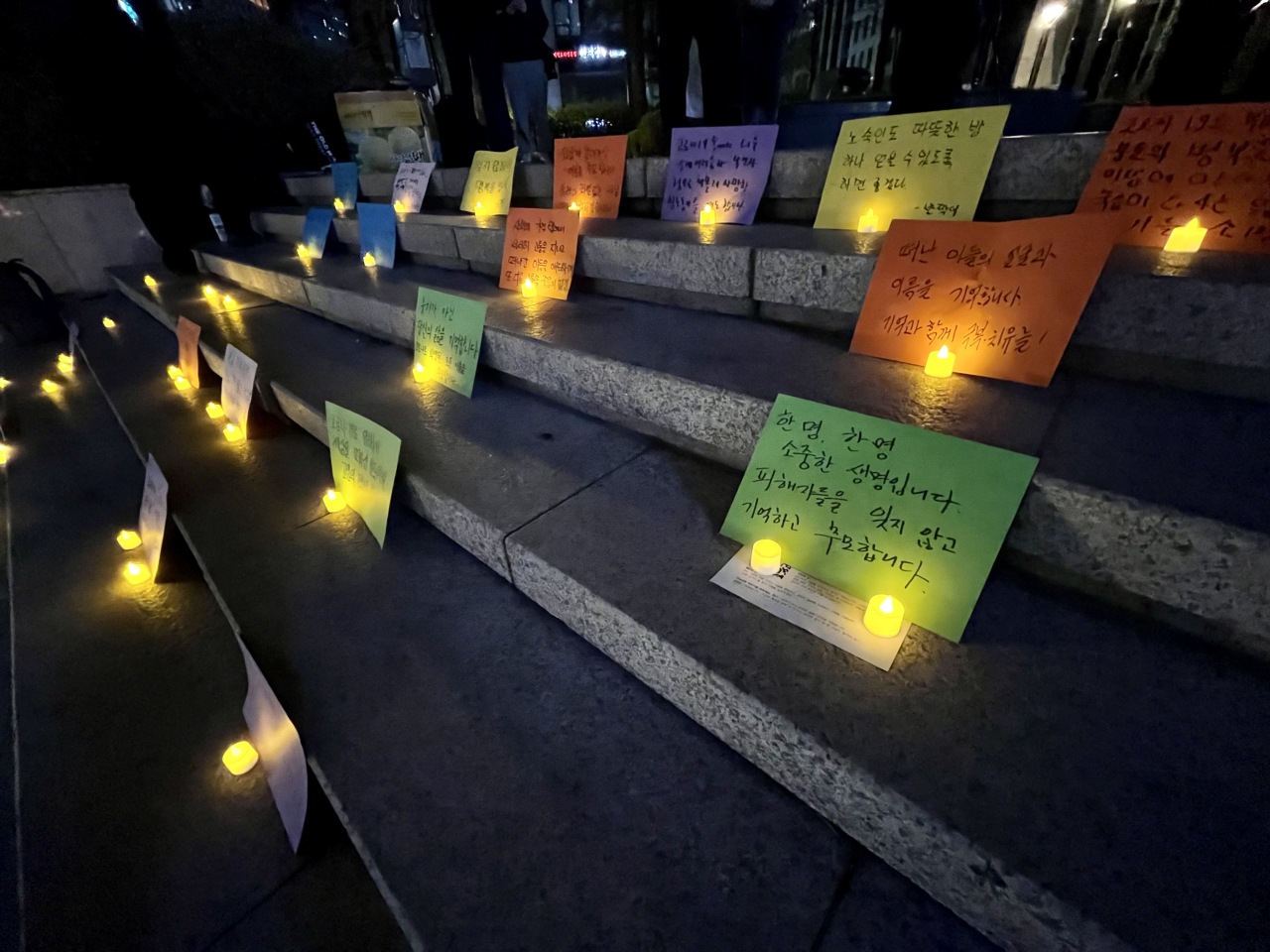 Flameless candles and paper sheets for writing messages were distributed to be displayed on the steps for a brief while. One message read: “No one should be alone in their final moments. I hope you are not lonely anymore.” (Kim Arin/The Korea Herald)