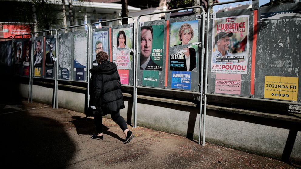 A woman walks past presidential campaign posters during the first round of the French presidential election in Saint-Denis, outside Paris on Sunday. The polls opened at 8am in France for the first round of its presidential election where up to 48 million eligible French voters will be choosing between 12 candidates. (AP)