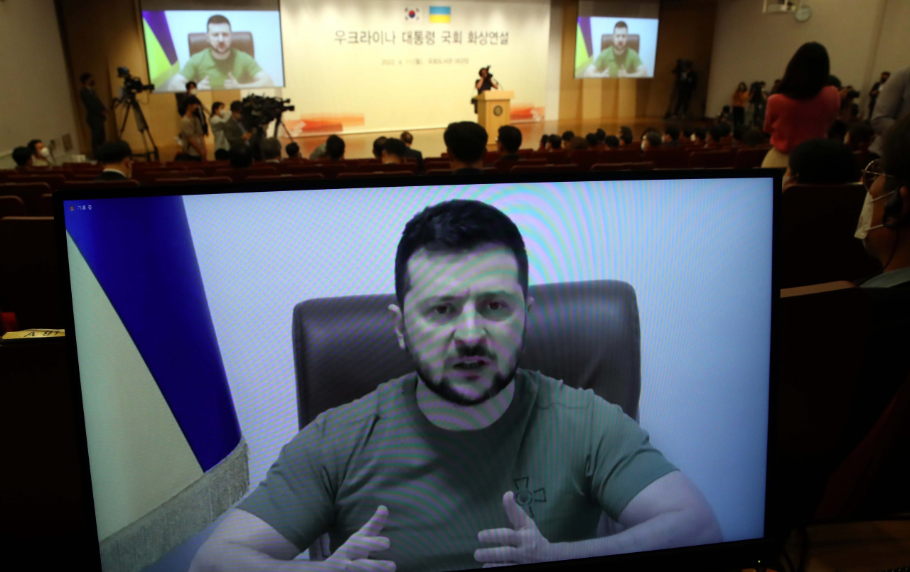 Ukrainian President Volodymyr Zelenskyy (on screen) speaks via video at the National Assembly in Seoul on Monday. Zelenskyy asked South Korea to provide military equipment to help his country fight against Russian aggression. (Yonhap)