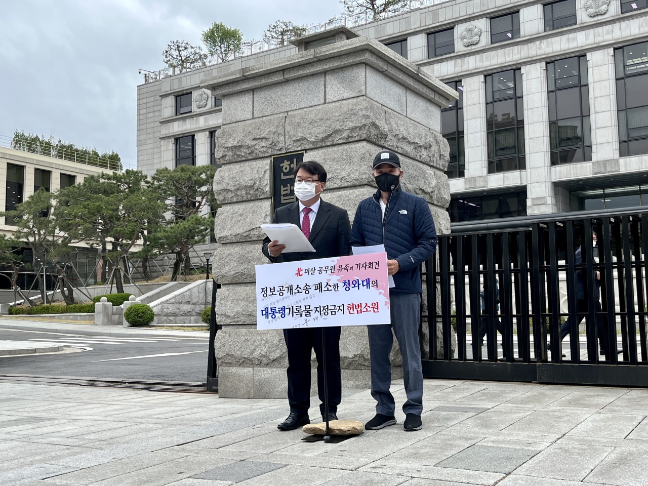 Lee Rae-jin (right), brother of an official killed by North Korea’s military while drifting in the sea, and Kim Ki-yun, a lawyer representing the family, speak to reporters outside the Constitutional Court in central Seoul on Wednesday. (Kim Arin/The Korea Herald)