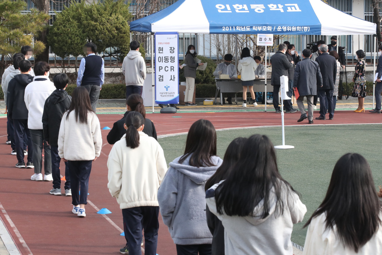 Students line up in front of a testing station installed at a middle school in Seoul (Yonhap)