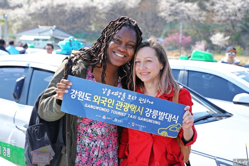 Foreigners pose with the taxis, operated by a local government for only expatriates, in Gwangwon Province’s Gangneung in April 2019. (Gangneung City)