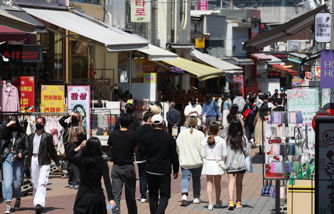 People walk down a street in central Seoul on Friday. Starting next week, South Korea will lift all COVID-19 social distancing rules, except the mask mandate, in the first big step toward a return to normalcy since the country reported its first COVID-19 outbreak in January 2020. (Yonhap)