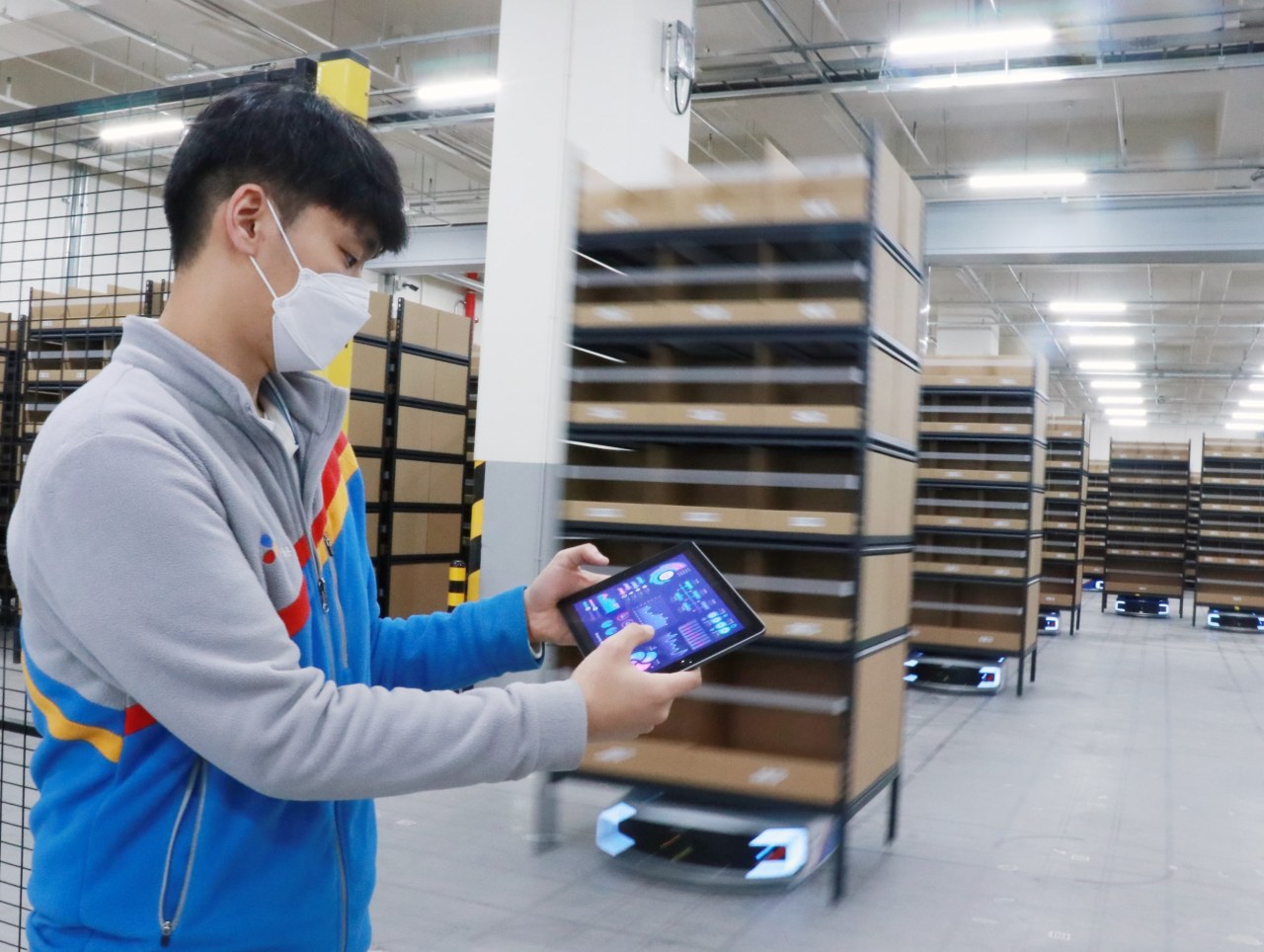A CJ Logistics staff operates an automated guided vehicle mobile robot that carries racks at a smart fulfillment center in Gunpo, Gyeonggi Province. (CJ Logistics)