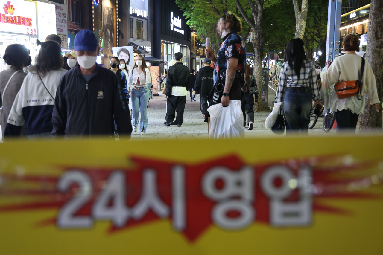 Passengers walk by a placard that reads “24/7 business operation.” (Yonhap)