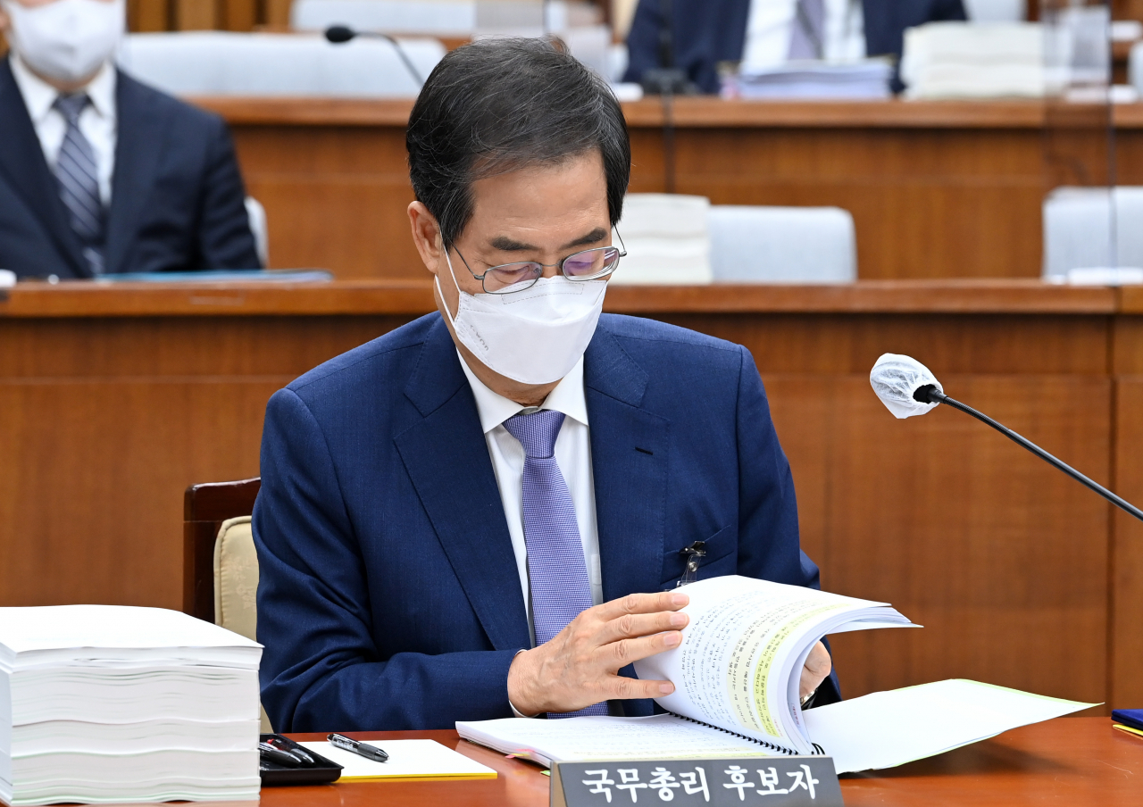 Han Duck-soo, the first prime minister nominee of President-elect Yoon Suk-yeol's incoming government, looks at materials during the second day of his parliamentary confirmation hearing at the National Assembly in Seoul on Tuesday. The ruling Democratic Party boycotted the hearing the previous day, citing 