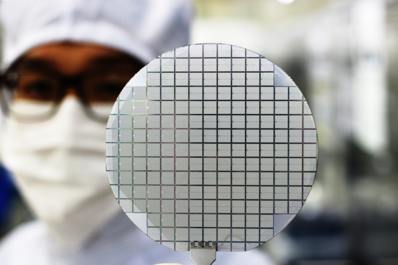 A Yes Power Technix worker poses for a photo with a silicon carbide semiconductor wafer. (SK Inc.)