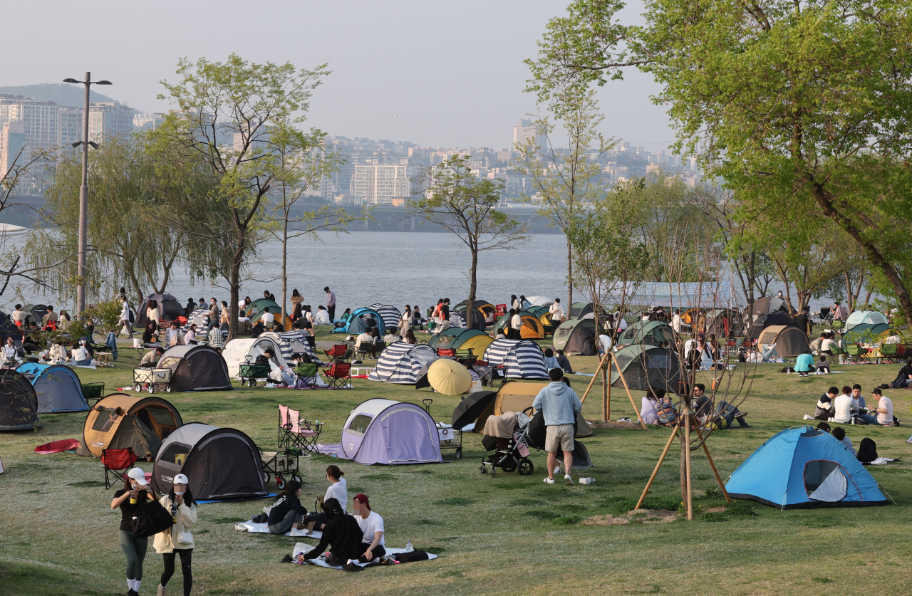 People lounge at a park along the Han River in Seoul, Sunday. (Yonhap)