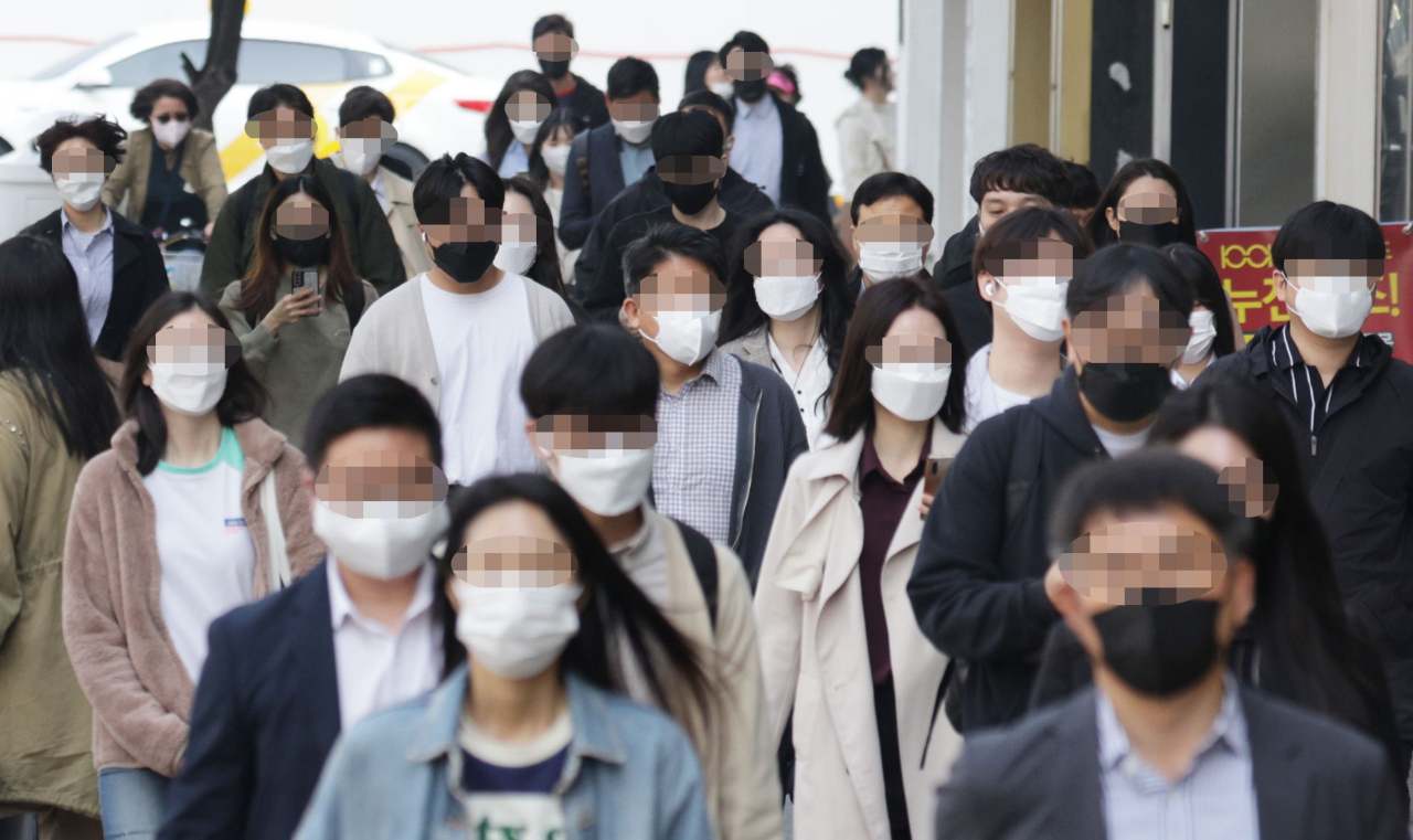 Commuters wearing masks walk on a street nearby the Yeouido subway station, Seoul, Monday. (Yonhap)