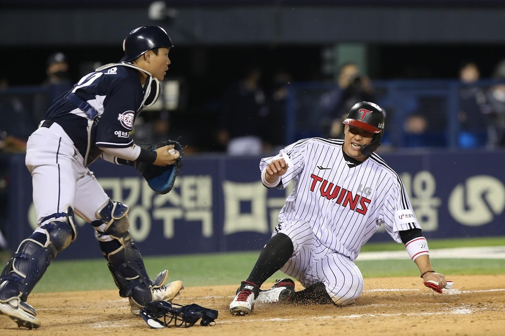 Yoo Kang-nam of the LG Twins (R) slides home safely ahead of Doosan Bears catcher Park Sei-hyok during the bottom of the fifth inning of a Korea Baseball Organization regular season game at Jamsil Baseball Stadium in Seoul on Tuesday, in this photo provided by the Twins. (LG Twins)