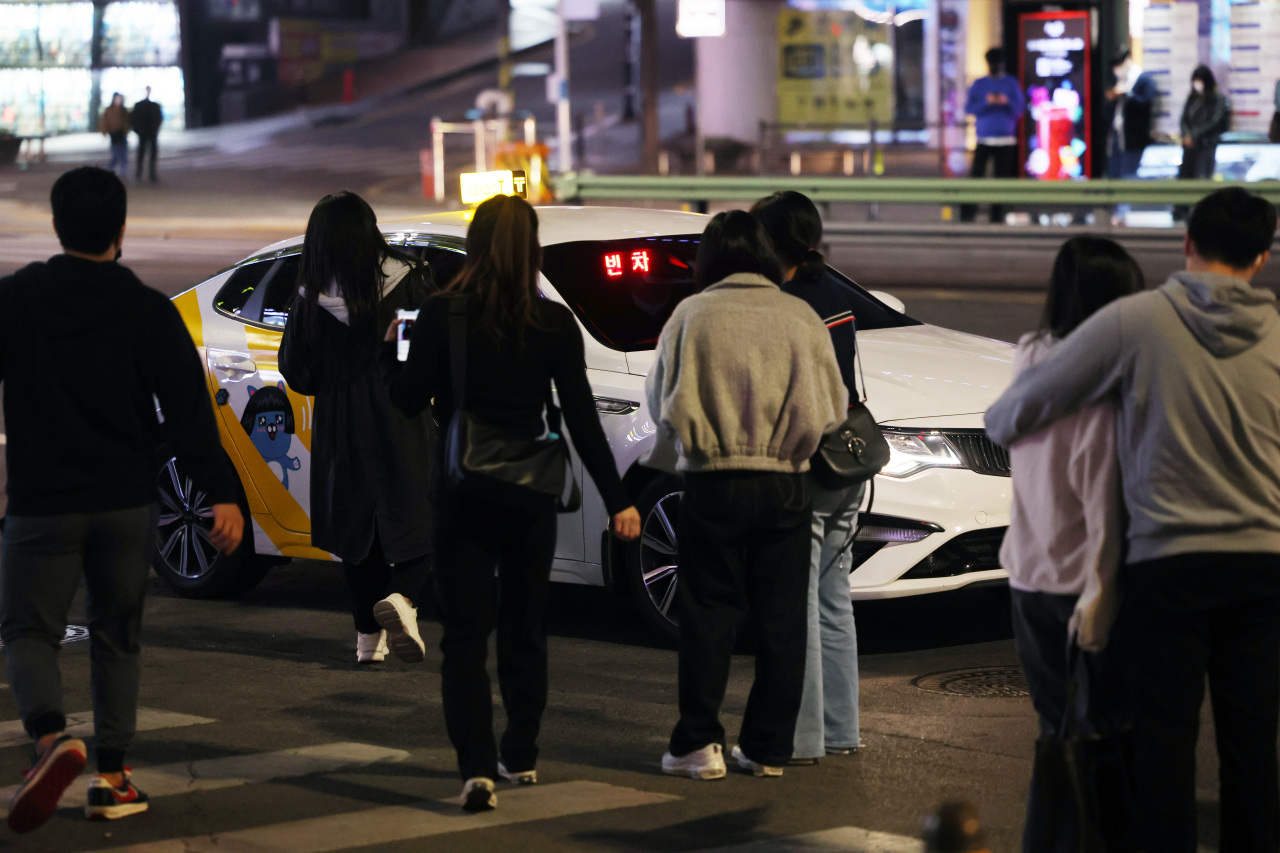 People wait for taxis on the roadside at night around Gangnam Station, Seoul. (Yonhap)