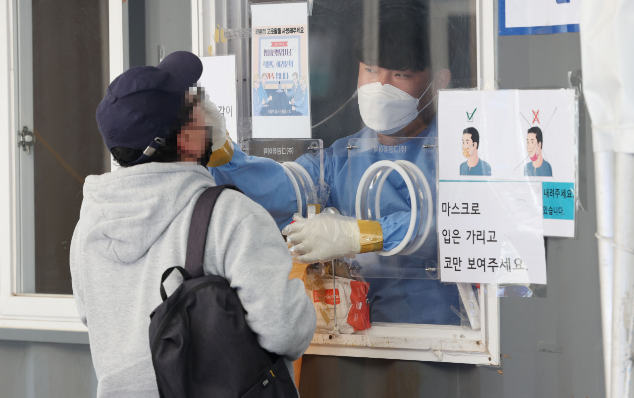 A health worker conducts a COVID-19 test on a citizen at a testing site in front of Seoul Station on May 5. (Yonhap)