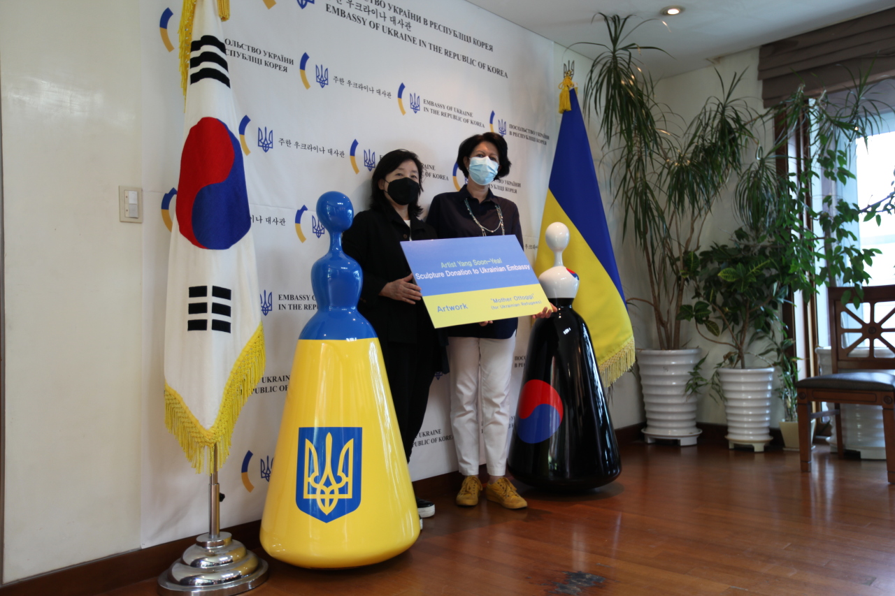 Artist Yang Soon-yeal (left) and Oksana Ponomarenko, spouse of Ambassador Dmytro Ponomarenko, pose for a photo on Friday with sculptures “Mother Ottogi” during a donation ceremony held at the Embassy of Ukraine in Seoul (D.K.KIM Foundation)