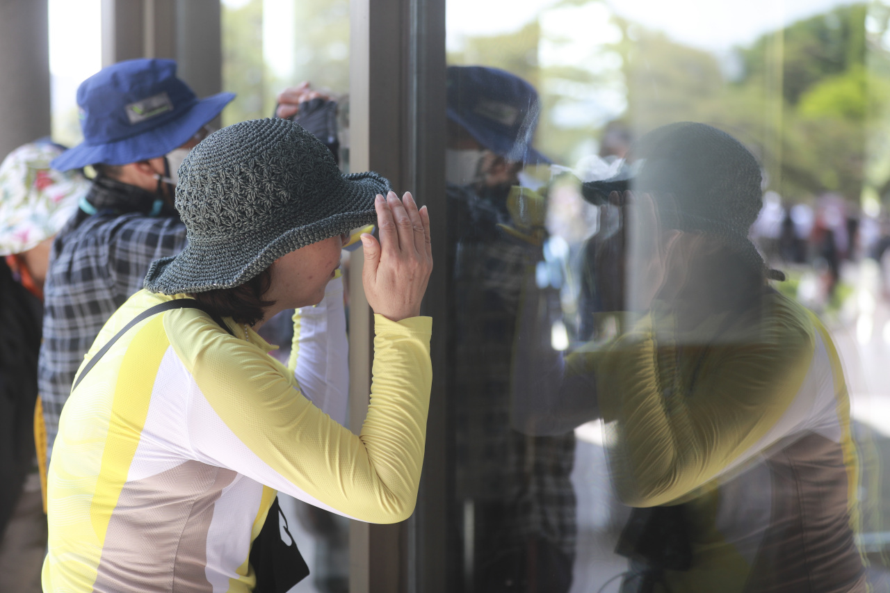 Visitors peer through the window of the main office building at Cheong Wa Dae on Tuesday. (Presidential Transition Committee Joint Press Corps)