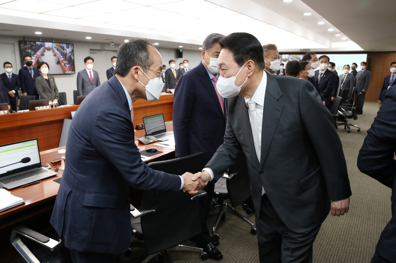 President Yoon Suk-yeol (right) shakes hands with Deputy Prime Minister and Finance Minister Choo Kyung-ho at an extraordinary Cabinet meeting in Seoul, Thursday. (Yonhap)