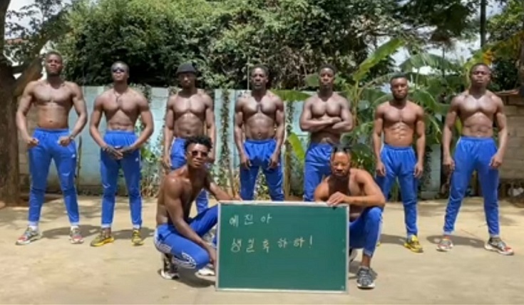 A screenshot of a video on YouTube channel “World Surprise Video,” featuring men in blue sweatpants standing around a sign that reads “Happy Birthday Ye-jin,” in Korean. (Courtesy of World Surprise Video)