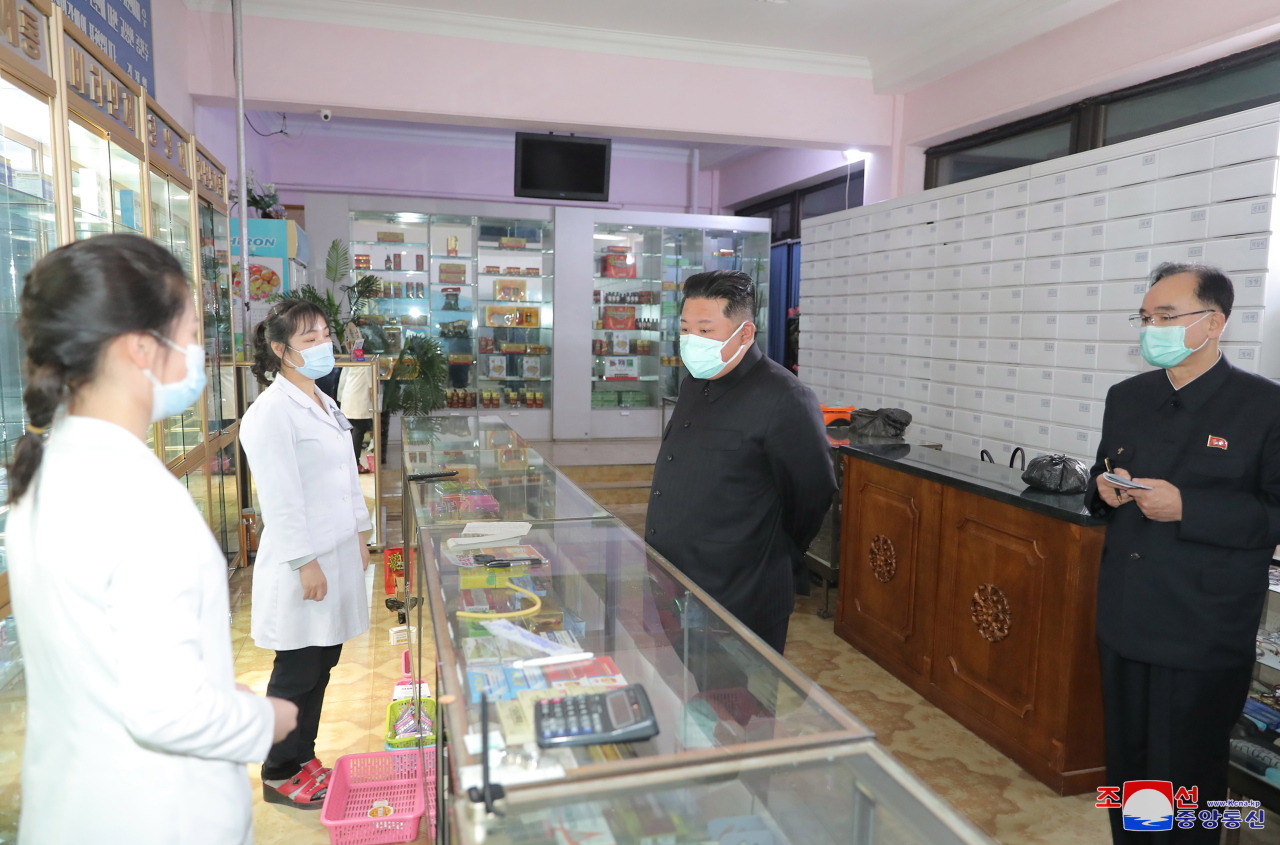 A photo released by the official North Korean Central News Agency (KCNA) shows North Korean leader Kim Jong-un (center) wearing a face mask while inspecting a pharmacy in Pyongyang, North Korea, Sunday. (Yonhap)