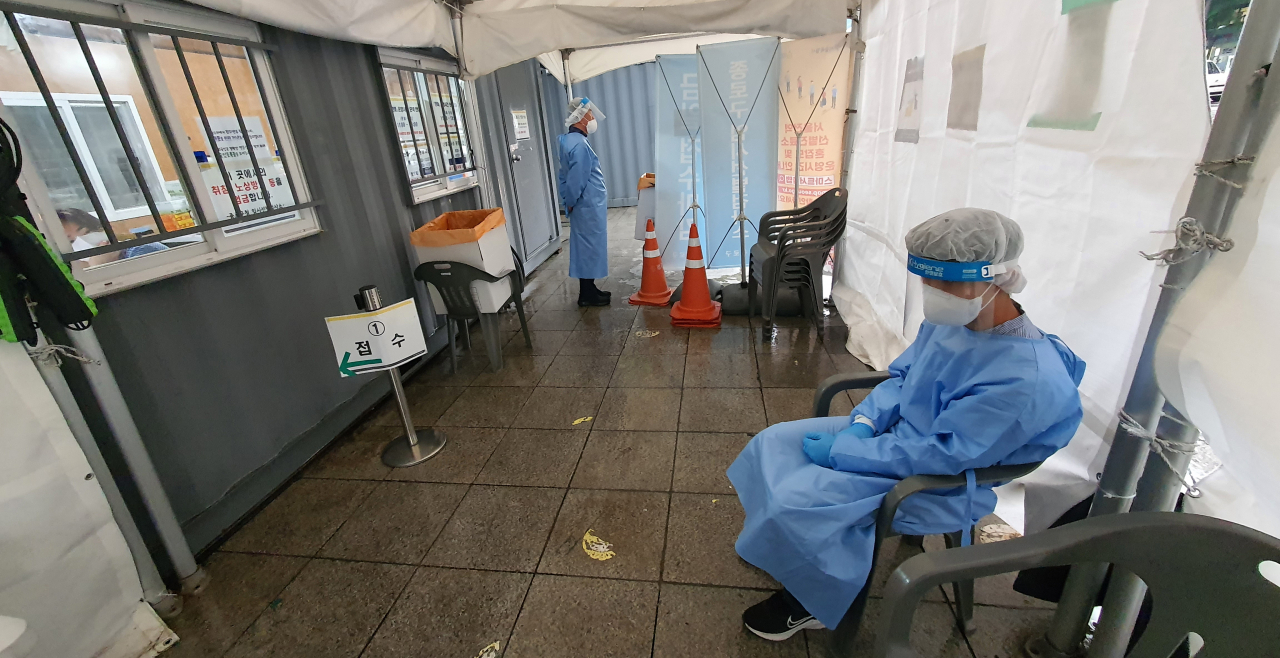 Medical workers stand by at a quiet COVID-19 testing booth in Seoul's central district of Jongno, in this photo taken Wednesday, amid a decline in the infection numbers. (Yonhap)