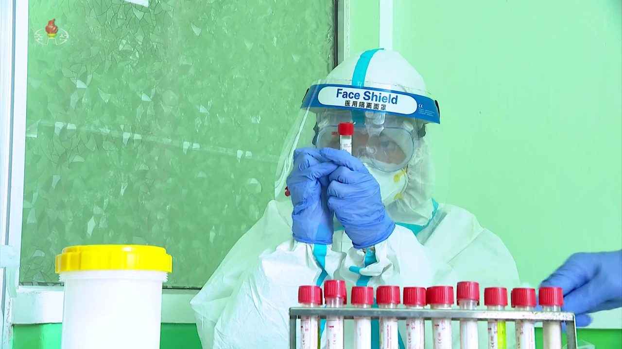 A North Korean medical worker wearing a face shield believed to be made in China collects test samples amid a surge in suspected coronavirus cases, in this photo captured from the North`s official Korean Central Television. (Yonhap)
