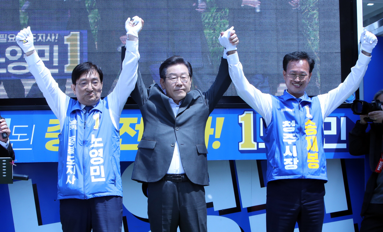 Lee Jae-myung (center), chief of the Democratic Party of Korea`s local elections campaign committee, rallies support with Noh Young-min (left), the party`s flagbearer for the North Chungcheong Province gubernatorial election, and Song Jae-bong (right), the liberal party`s candidate for Cheongju mayoral election, during a campaign event held Sunday. (Yonhap)