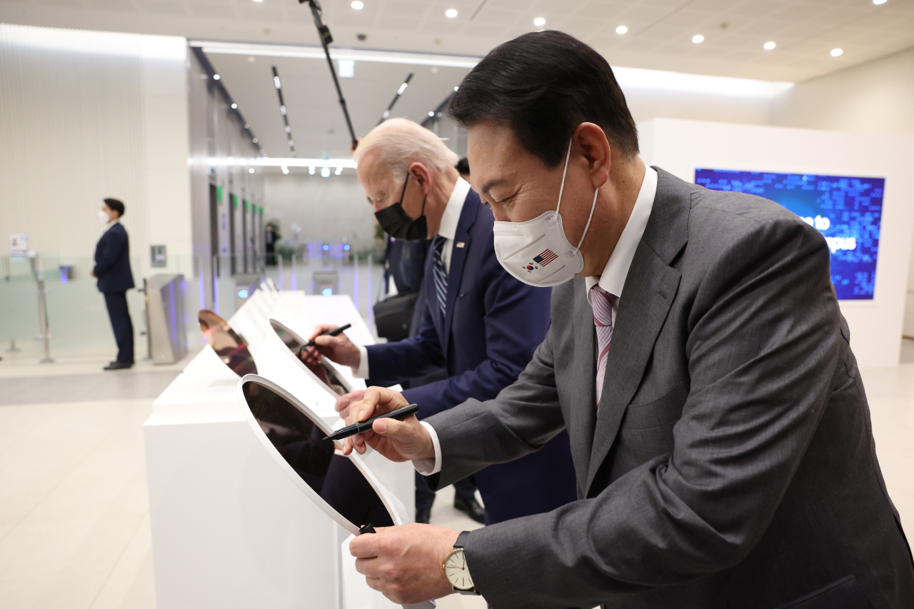 Presidents Yoon Suk-yeol and Joe Biden put their signatures on semiconductor wafers at Samsung Electronics’ chip manufacturing plant in Pyeongtaek, Gyeonggi Province, Friday. (Yonhap)