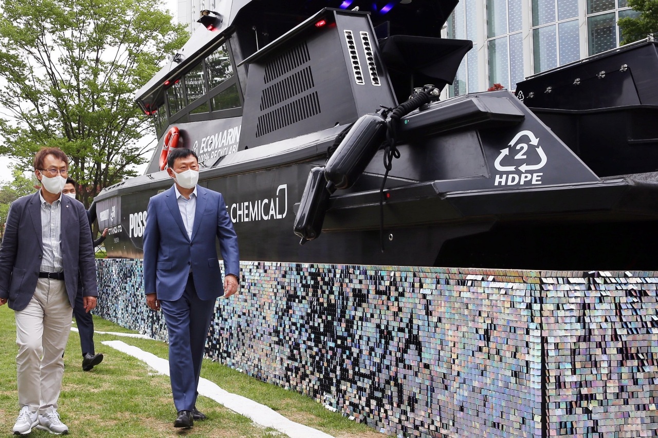 Shin Dong-bin, CEO of Lotte Group (right), walks by a boat named “Possibility” during Lotte Chemical’s exhibition “Every Step for Green” held on May 19. (Lotte Group)