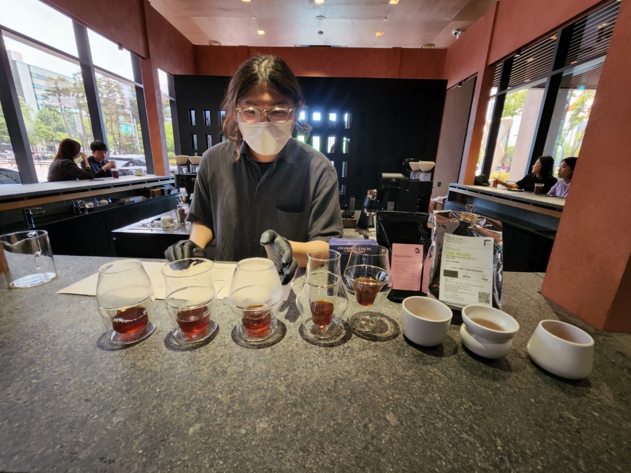 A staff member explains flavors of drip coffee served in eight different cups at Conflict Store. The coffee parlor in Jamsil-dong, Songpa-gu, Seoul, offers three tasting courses featuring different brews. (Choi Jae-hee / The Korea Herald)