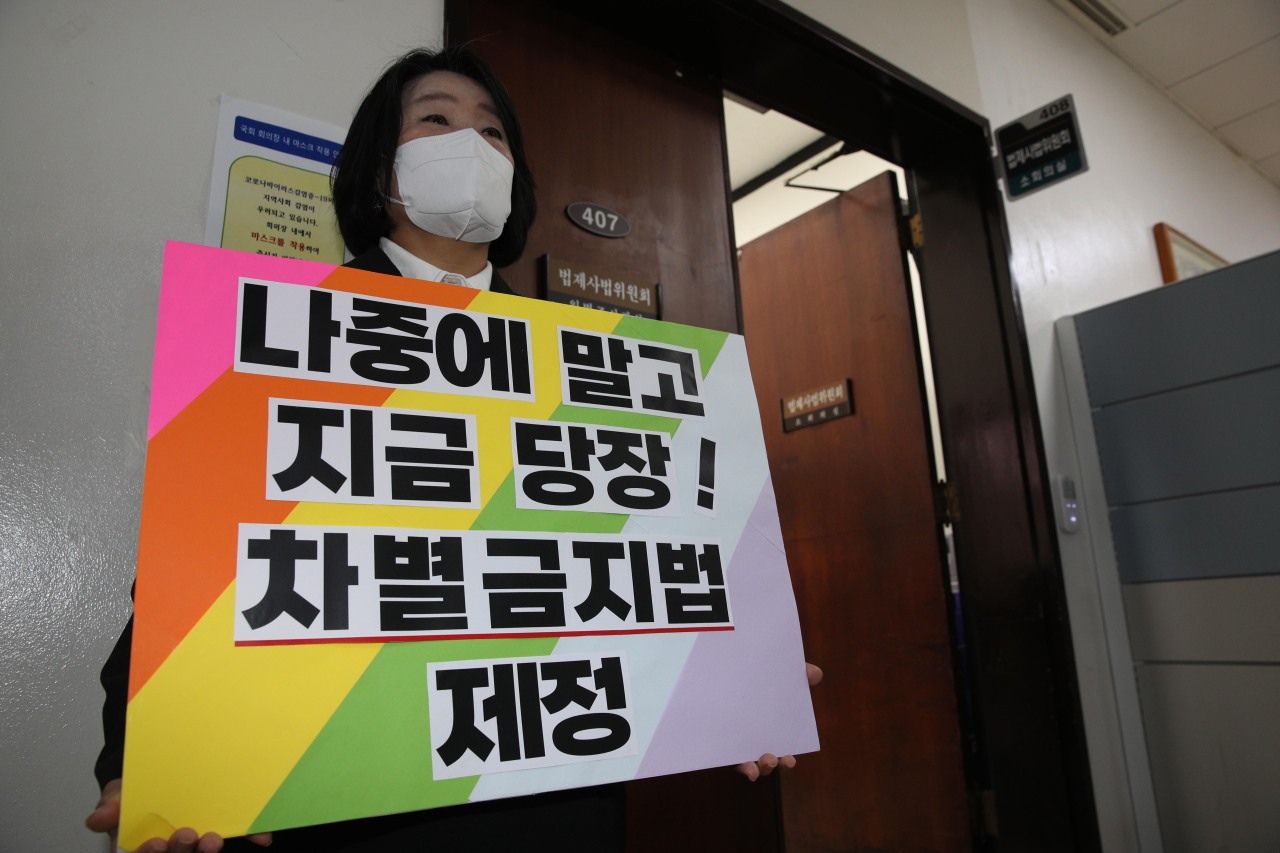 Rep. Youn Mee-hyang, a former human rights activist who co-proposed the anti-discrimination act, holds a sign that says, “Not later, right now! Enact anti-discrimination act” at the National Assembly prior to the parliamentary legislation and judiciary committee session on Wednesday. (Yonhap)