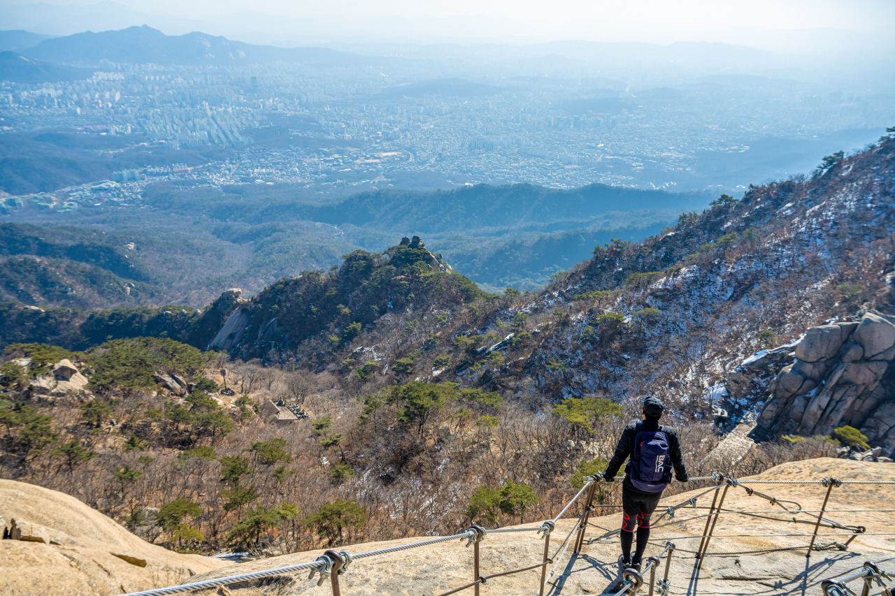 A hiker looks at the view of Seoul from the Baegundae peak of Bukhansan. (STO)