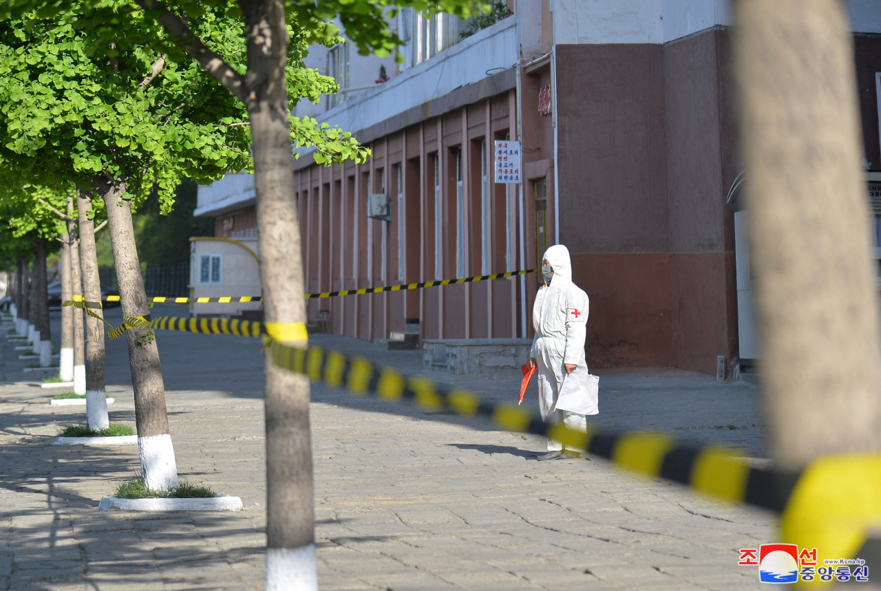 This file photo, released by the North's official Korean Central News Agency on May 17, 2022, shows a health care worker on a closed-off sidewalk in Pyongyang amid the country's COVID-19 outbreak. (KCNA)