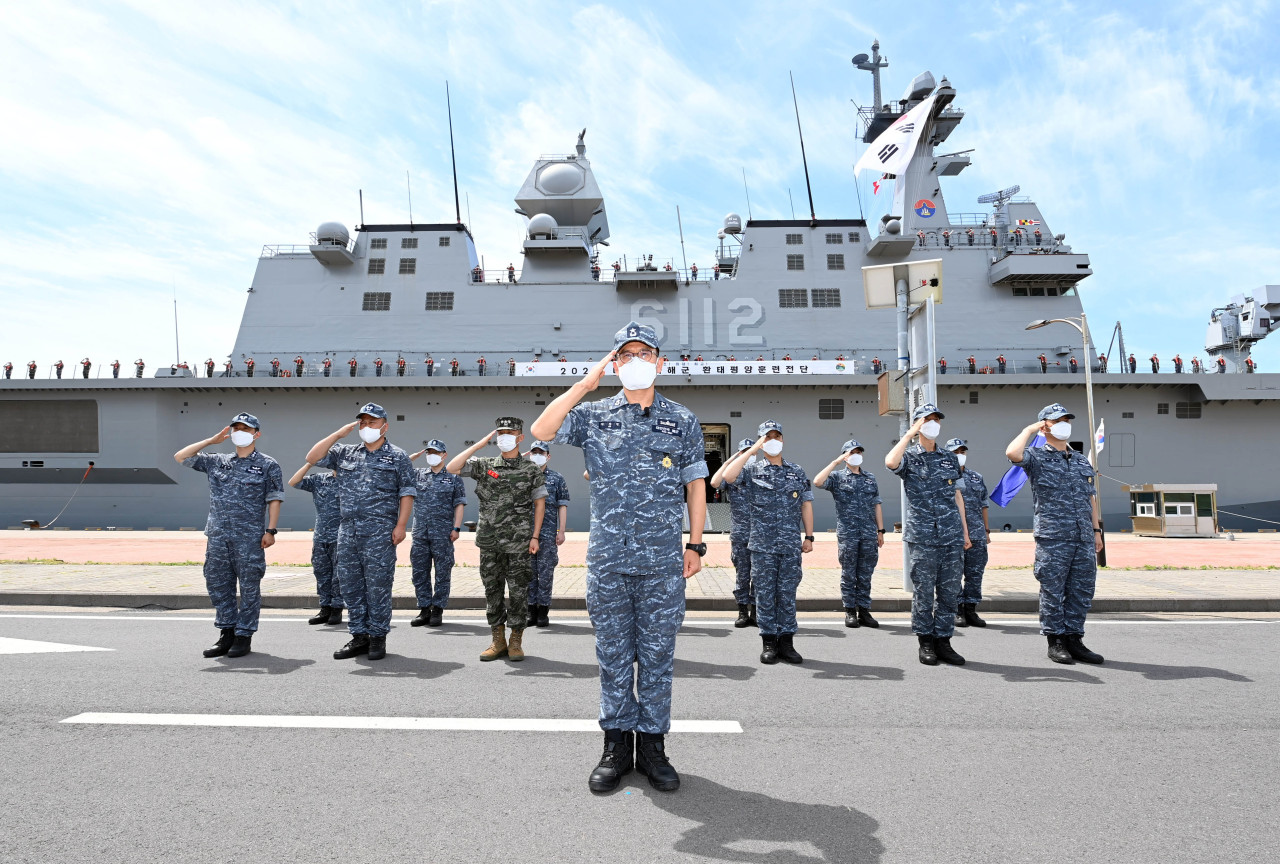 This photo, released by the Navy on May 31, 2022, shows Rear Adm. An Sang-min (front) and members of his fleet saluting at a naval base on South Korea`s southern Jeju Island on May 31, 2022, before they depart to join the Rim of the Pacific Exercise, a U.S.-led biennial multinational maritime exercise. The Marado (behind them), a 14,500-ton amphibious assault ship, was dispatched on the mission set for June through early August in waters off Hawaii. (Yonhap)
