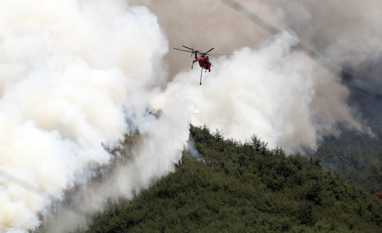 Firefighter put out the flames with a helicopter in Miryang-si, Gyeongsangnam-do on Tuesday. (Yonhap)