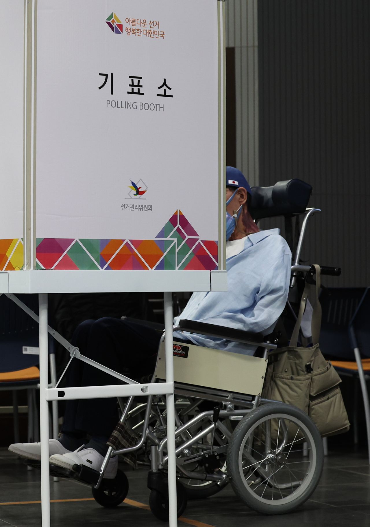 A man in a wheelchair is preparing to vote at a polling booth in Seoul during Wednesday’s local elections. (Yonhap)