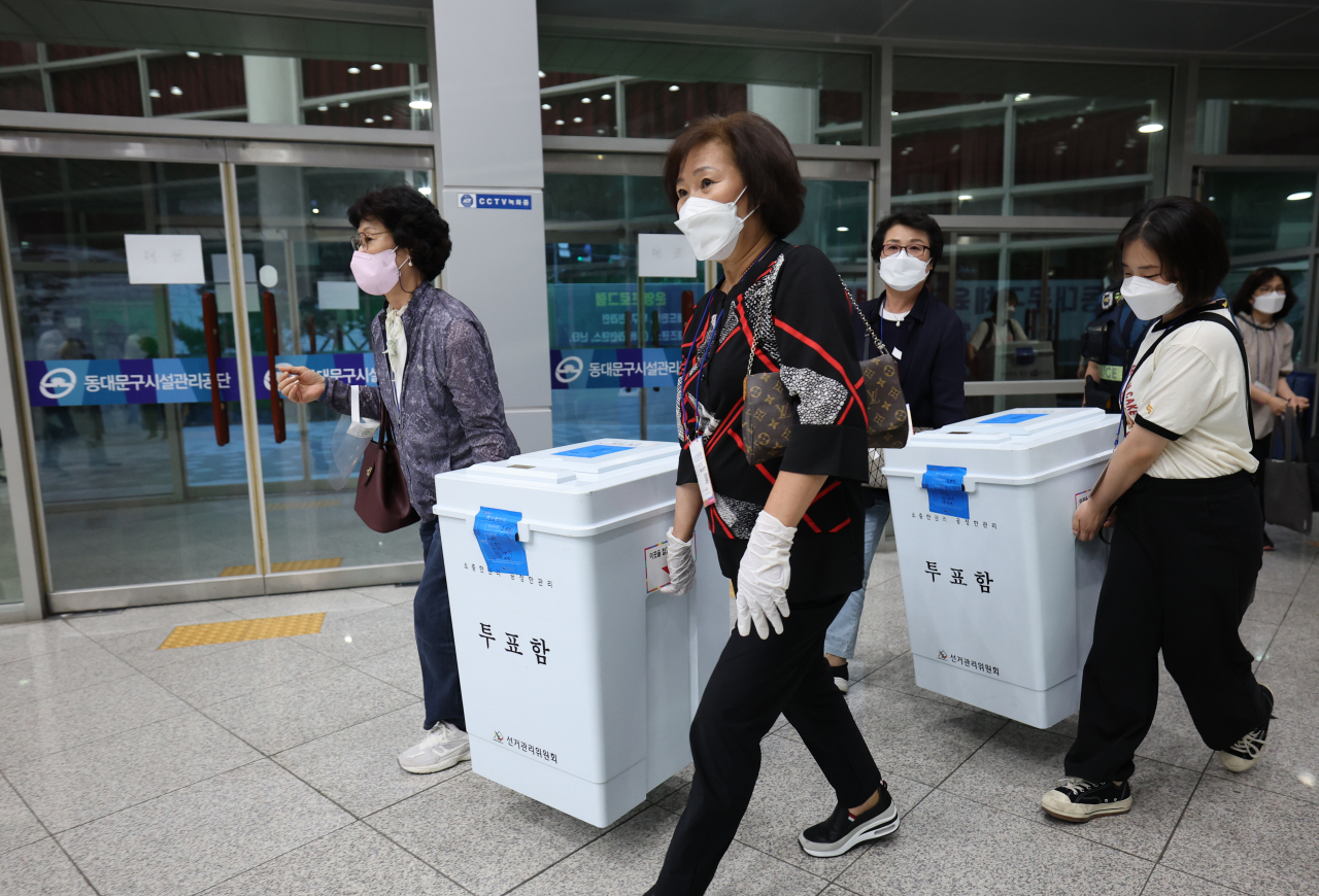 Ballot boxes are carried away to be tallied, Wednesday night. (Yonhap)