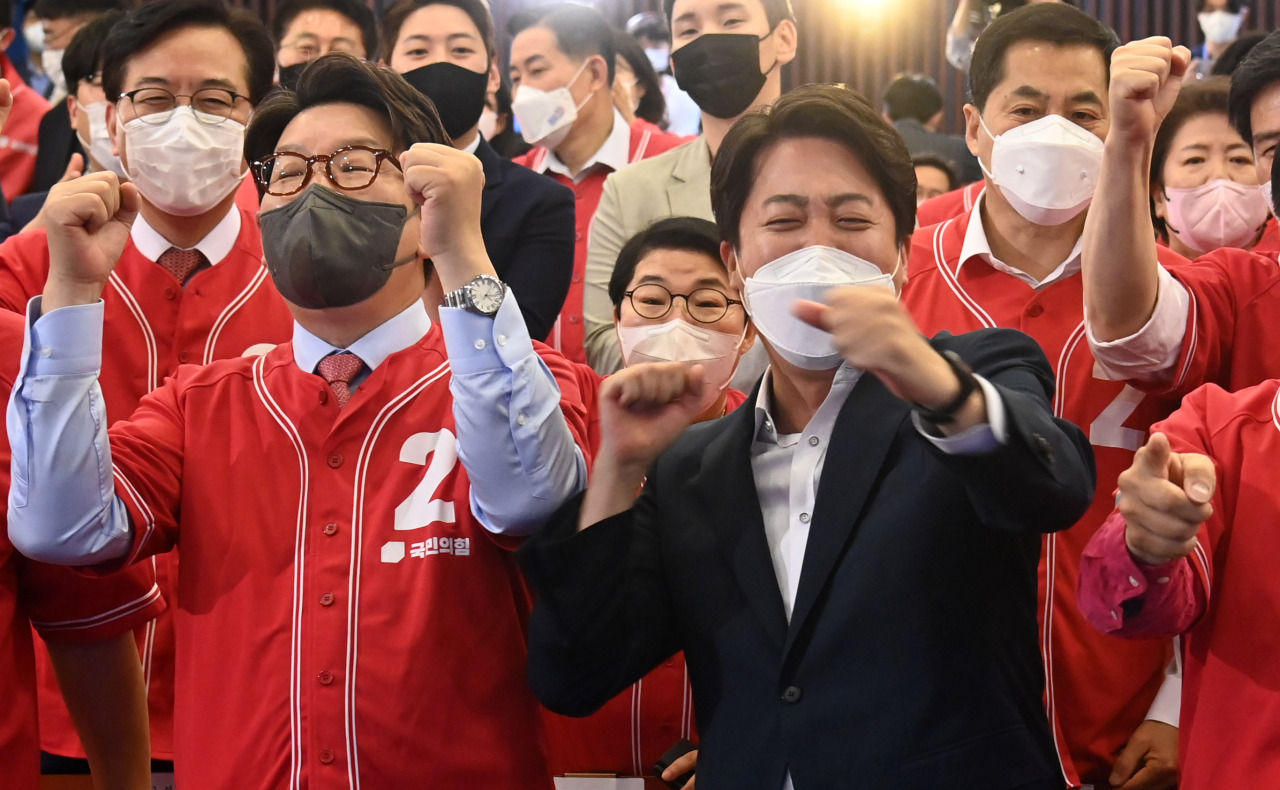 Members of the ruling People Power Party including Chairman Lee Jun-seok (right) and Floor Leader Kweon Seong-dong (left) cheer as they watch the exit poll results at the National Assembly in Seoul on Wednesday. (Yonhap)