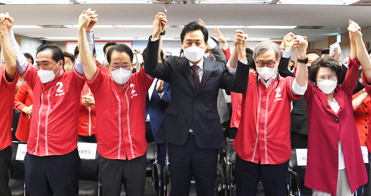 Oh Se-hoon (center), the People Power Party’s mayoral candidate for Seoul, and his aids cheer at his campaign office in central Seoul, after an exit poll was announced, Wednesday. (Yonhap)