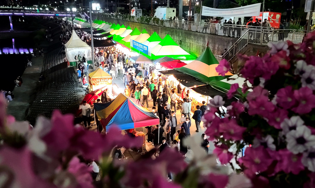 People visit booths set up at an open-air market along the Namdaecheon stream at the Gangneung Danoje Festival in Gangneung, Gangwon Province, Tuesday. (Yonhap)