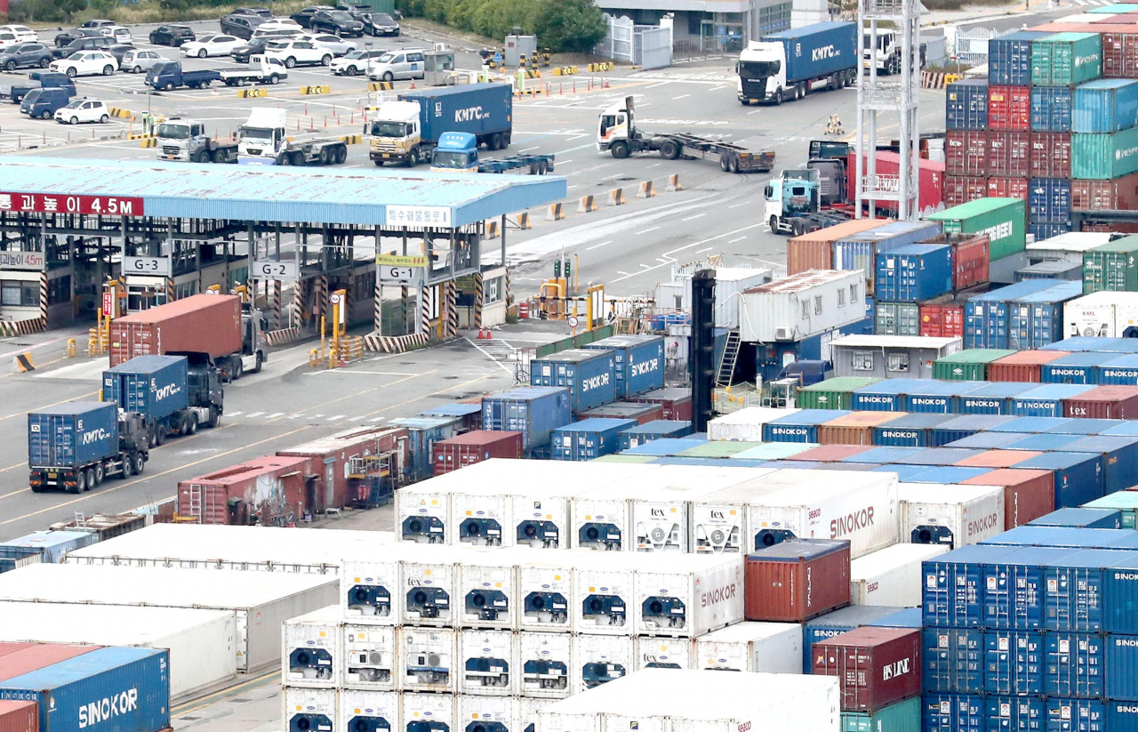 Trucks transport containers at a pier in Busan on Monday, a day before unionized cargo truckers were set to go on a general strike. (Yonhap)