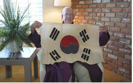 James Lantz, a US Marine veteran who served in the 1950-53 Korean War, poses for a photo with a South Korean flag received from a Korean Marine, in this photo released by the Ministry of Patriots and Veterans Affairs on Tuesday. (Ministry of Patriots and Veterans Affairs)