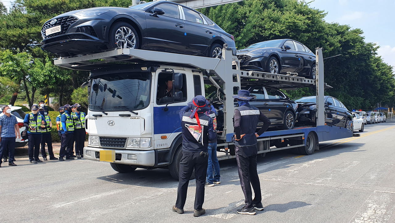 Unionized truckers of the militant Korean Confederation of Trade Unions attempt to stop a car hauler from leaving Hyundai Motor Co.'s plant in the city of Asan, about 85 kilometers south of Seoul, on Wednesday. (Yonhap)