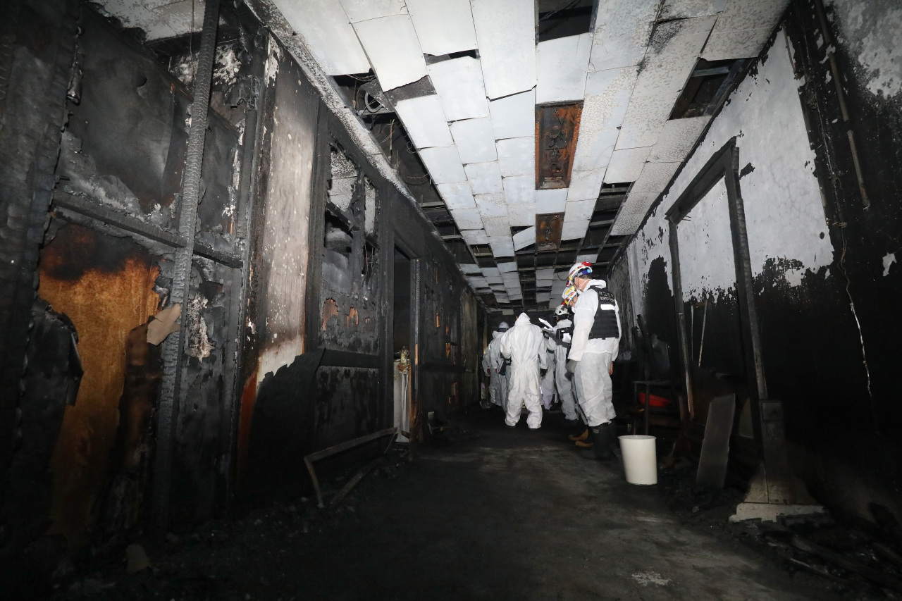 Forensic officers inspect the scene of arson attack on Friday. (Yonhap)