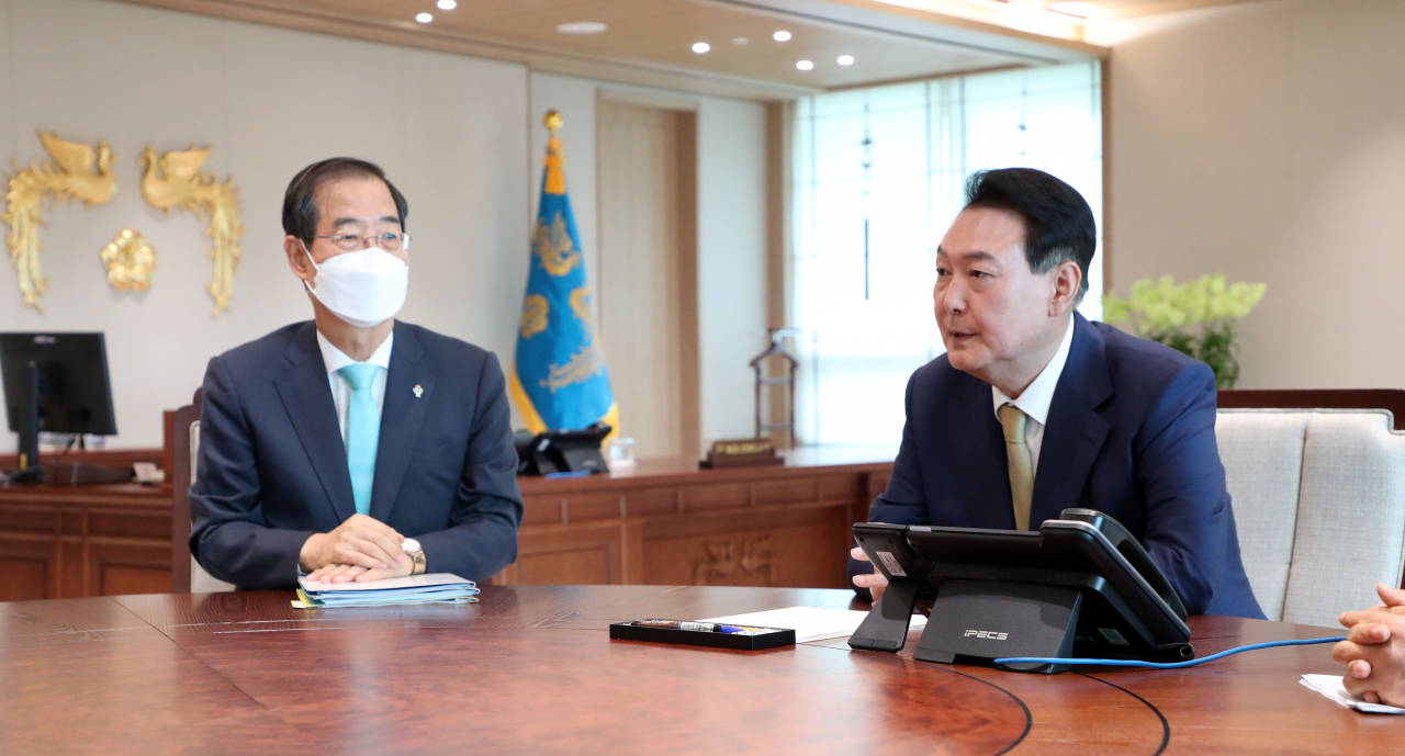 President Yoon Suk-yeol (R) talks with Prime Minister Han Duck-soo during their weekly meeting at the presidential office in Seoul on Monday. (Yonhap)