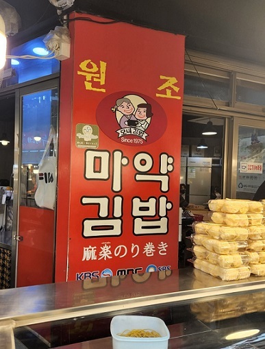 A picture of a storefront sign installed by Monyeo Gimbap, one of many food vendors in Gwangjang traditional market that sell “mayak gimbap,” seaweed-rolled rice with a hot mustard sauce. (Choi Jae-hee / The Korea Herald)