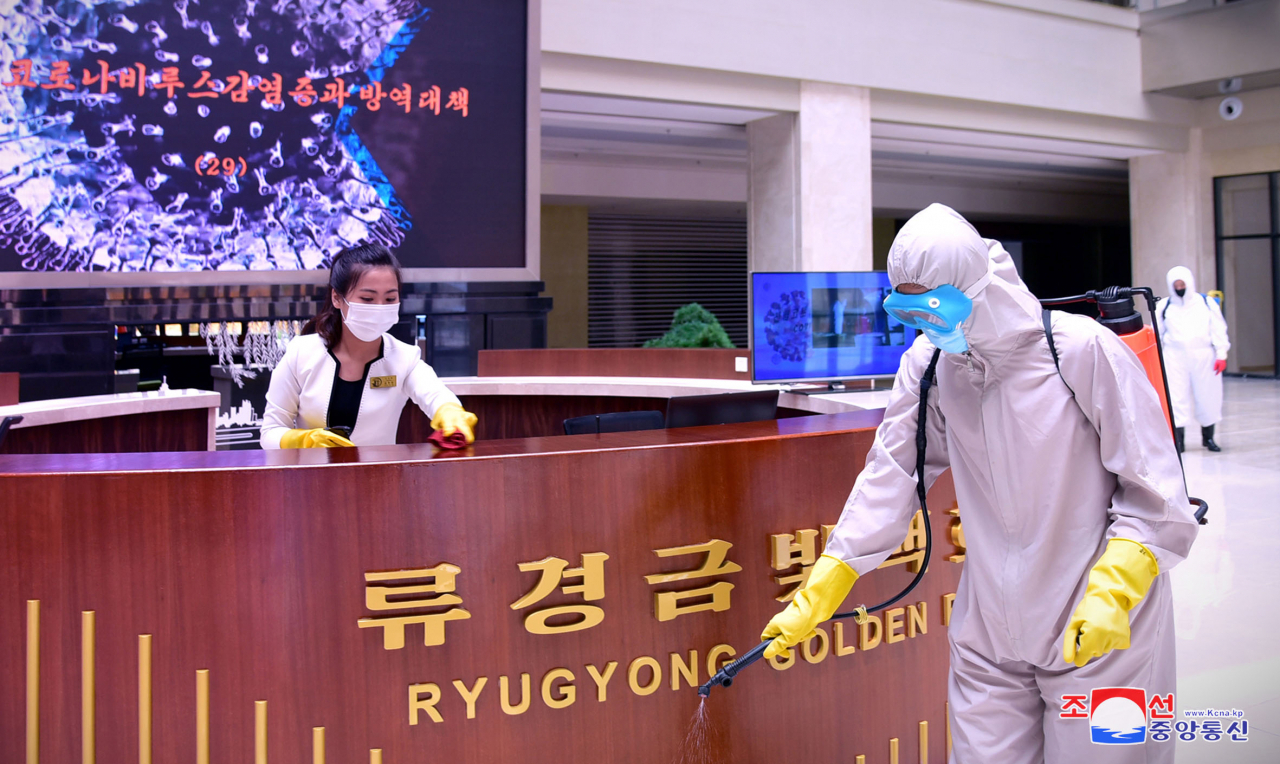 In this photo released by the North's official Korean Central News Agency last Wednesday, North Korean workers conduct disinfection work at Ryugyong Golden Mall in Pyongyang. (KCNA)