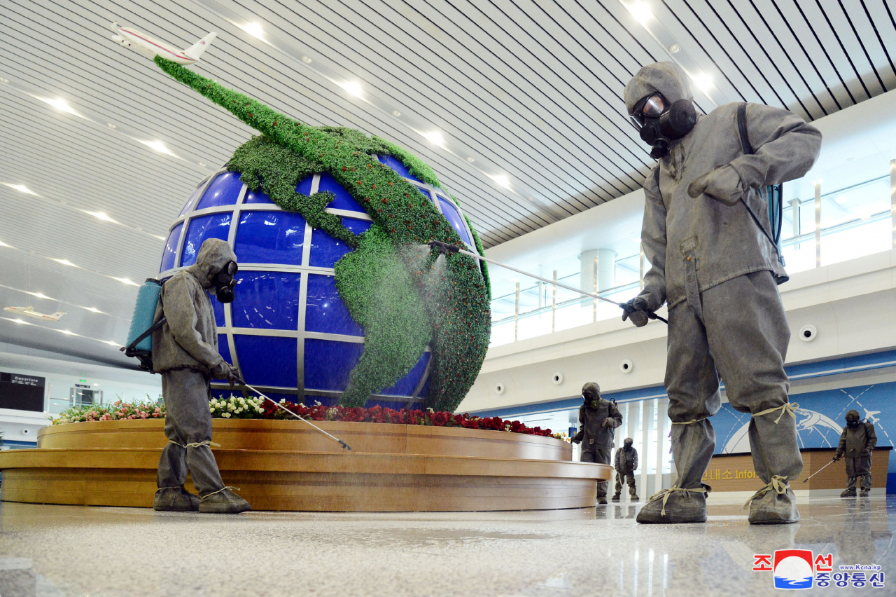 Quarantine officials spray disinfectant at Pyongyang International Airport in the North Korean capital amid the highest-level alert on the coronavirus, in this undated file photo released by the North's Korean Central News Agency on June 10. (KCNA)
