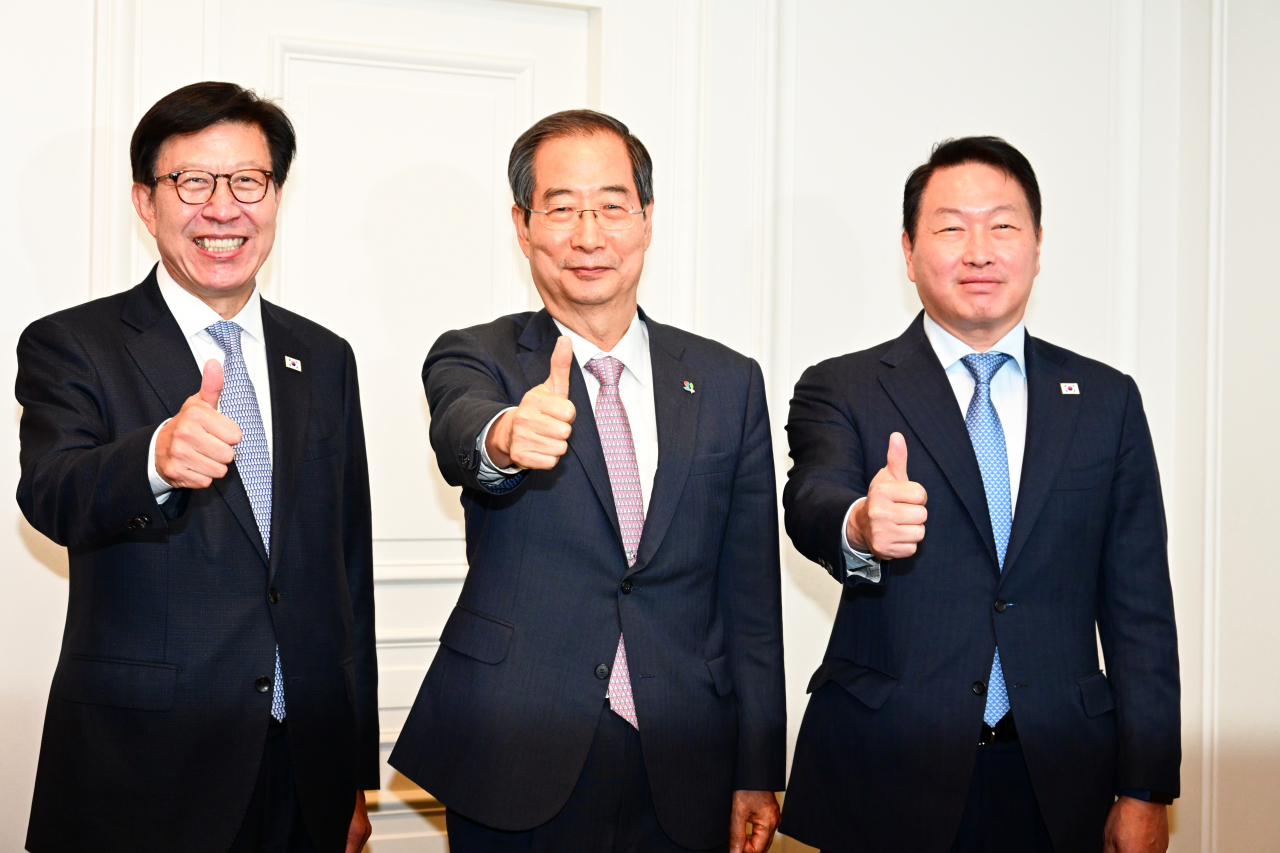 Prime Minister Han Duck-soo (C), Busan Mayor Park Heong-joon (L) and SK Group Chairman Chey Tae-won pose for the camera ahead of a general assembly of the Bureau International des Expositions in Paris on Monday, in this photo provided by Han's office. (Han's office)