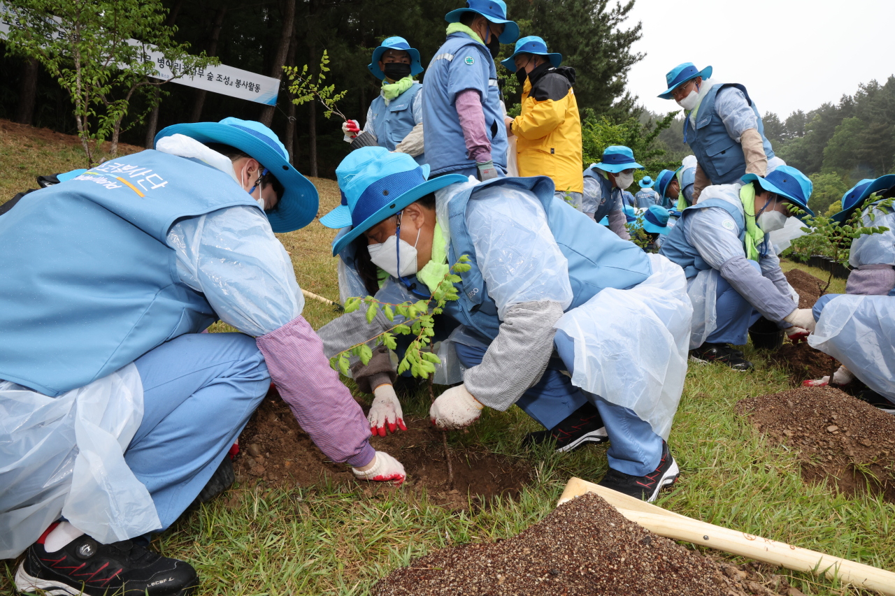 Posco Vice Chairman Kim Hak-dong (center) plants a goldenrain tree sapling at Hwanho Park in Pohang, North Gyeongsang Province on June 14, as part of Posco‘s 2022 “Global Model Citizen Week.” (Posco)