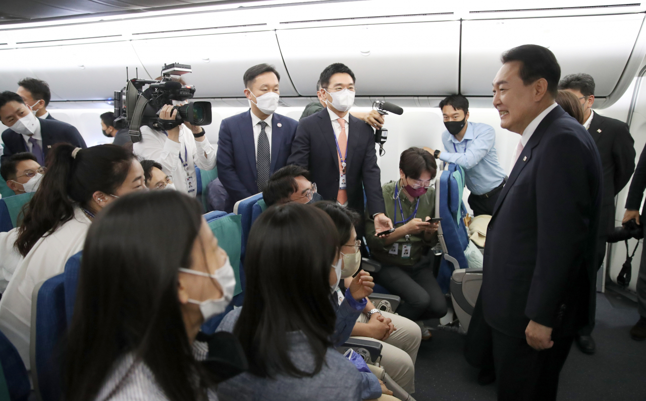 South Korean President Yoon Suk-yeol (R) greets reporters on the presidential plane on his way to Madrid on Monday, to attend the NATO summit on his first overseas trip as president. (Yonhap)